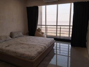 1 dormitorio con cama y ventana grande en D ocean view, en Surat
