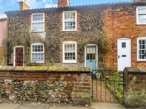 an old brick house with white windows and a blue door at September Cottage in Wenhaston