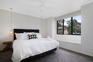 a white bedroom with a large bed and a window at Alpine Knights Stylish Luxury in Bright