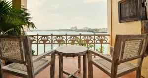 een tafel en stoelen op een balkon met uitzicht op het water bij Tulia Old Town in Mombasa