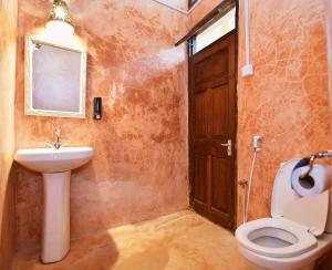 een badkamer met een toilet, een wastafel en een deur bij Tulia Old Town in Mombasa