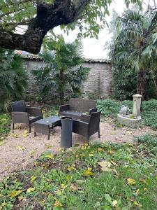 um parque com dois bancos, uma mesa e uma árvore em chambre violette coté aéroport calme charmante em Pusignan