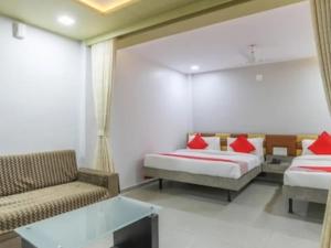 Habitación con 2 camas, sofá y mesa. en HOTEL CM PALACE & GUEST HOUSE & P.G ROOMS, en Kalol