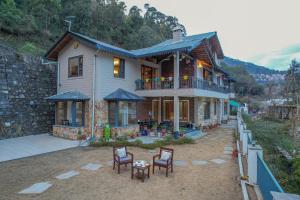 une maison avec des chaises et des tables devant elle dans l'établissement SaffronStays Wood Sparrow, à Bhimtal