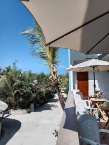 a patio with chairs and an umbrella and a palm tree at Hanifaru Beach Inn in Baa Atoll