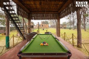 a pool table with balls on it in a pavilion at StayVista's Chahal Farmstay - Lake & Farm-View Villa with Terrace, Lawn featuring a Gazebo & Indoor-Outdoor Games in Amritsar