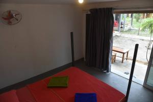 - une chambre avec un lit rouge dans une pièce avec une fenêtre dans l'établissement Big Head Bungalows, à Koh Rong Sanloem