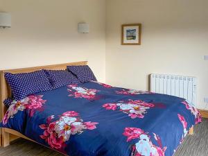 un letto con un piumone blu e fiori sopra di Brookfields a Middleham