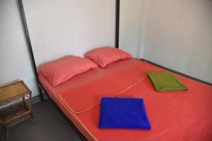 - un lit rouge avec deux oreillers et un livre bleu dans l'établissement Big Head Bungalows, à Koh Rong Sanloem