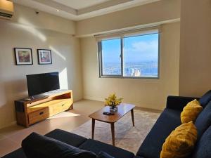 a living room with a blue couch and a tv at Simple and elegant 2BR with washer in Manila