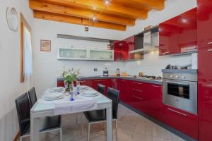 una cocina con armarios rojos y una mesa con sillas. en [Marostica - Villa with Swimming Pool] Netflix - WiFi en Sarcedo