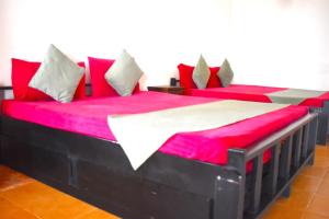 2 łóżka w pokoju z biało-czerwonymi poduszkami w obiekcie Thalladi Holiday Bungalow w mieście Mannar