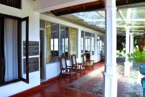 a porch of a building with chairs and windows at Thalladi Holiday Bungalow in Mannar