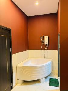 a large white tub in a bathroom with red walls at NHÀ NGHỈ TÚ SỰ in Vĩnh Long