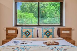 STAR HOLIDAY VILLAS في أنجونا: غرفة نوم بسرير مع نافذة كبيرة
