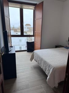 a bedroom with a bed and a television and a window at Atico padre Aldama in Sanlúcar de Barrameda