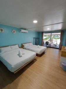 two beds in a room with blue walls and wooden floors at Home Away Tioman Island in Tioman Island