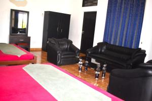 a bedroom with two black leather chairs and a bed at Thalladi Holiday Bungalow in Mannar