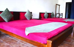 Thalladi Holiday Bungalow في منار: سريرين في غرفة ذات أغطية وردية