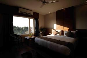 迪布鲁加尔Hotel Tree Fern的有一张大床和一扇窗户的酒店房间