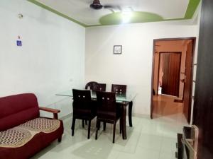 a living room with a dining room table and a red couch at Kainchi daam Road Nainital full 2bhk in Nainital