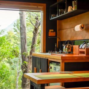 cocina con encimera, ventana y mesa en Refugios de bosque en Coñaripe, en Coñaripe