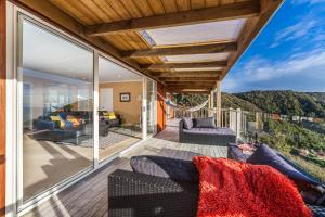 a patio with a couch and chairs on a balcony at Romantic Piha in Piha