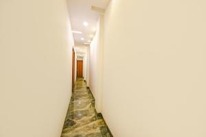 um longo corredor com paredes brancas e pisos de pedra em FabExpress Royal MG em Ludhiana
