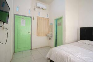 Lampung的住宿－Lyfriska Residence Lampung RedPartner，一间设有绿门、一张床和水槽的客房