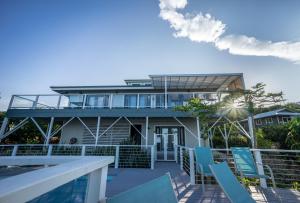 een huis op het strand met een balkon en stoelen bij The Pineapple Palace in Papa Bay Estates