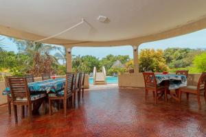 una sala da pranzo con tavolo, sedie e piscina di Sal & Lala Castle watamu a Watamu