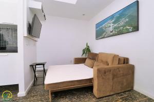 een woonkamer met een bank en een tv aan de muur bij Sala quarto c/ 2 banheiros para 4 pessoas in Rio de Janeiro