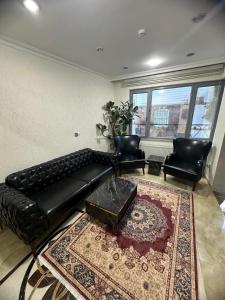 a living room with a black leather couch and two chairs at BİG ORANGE HOTEL in Istanbul