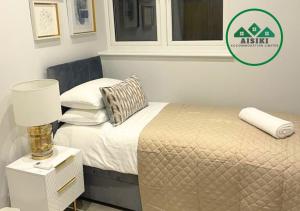 1 dormitorio con 1 cama con lámpara y ventana en FW Haute Apartments at Enfield, Pet-Friendly Ground Floor 3 Bedrooms and 2 Bathrooms Flat with King or Twin beds with Garden and FREE WIFI and PARKING en Londres