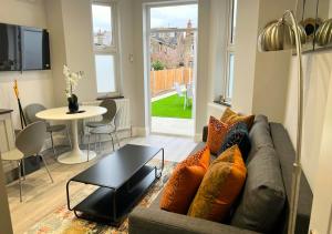 a living room with a couch and a table at FW Haute Apartments at Enfield, Pet Friendly Ground Floor 3 Bedrooms and 2 Bathrooms Flat with King or Twin beds with Garden and FREE WIFI and FREE PARKING in London