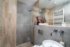 ein Bad mit einer Dusche und einem Waschbecken in der Unterkunft Apartaments 24 Premium Green in Breslau