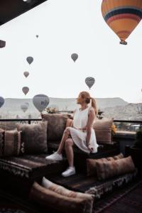 Eine Frau, die auf einer Couch mit einem Heißluftballon sitzt. in der Unterkunft Royal Stone Houses - Goreme in Goreme