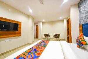 a hotel room with a bed and two chairs at FabHotel Orio I in Ludhiana
