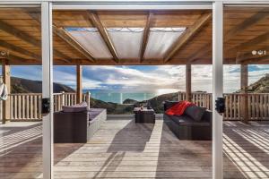 a covered deck with couches and a view of the mountains at Romantic Piha in Piha