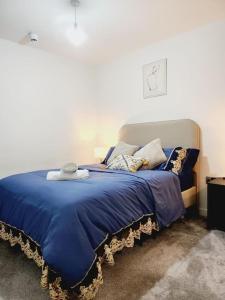 a bed with a blue blanket and pillows on it at Flat close to Manchester Picadilly station in Manchester
