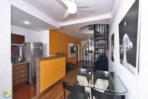 une salle à manger avec une table en verre et une cuisine dans l'établissement Cobertura duplex 2 quartos com terraço e piscina, à Rio de Janeiro