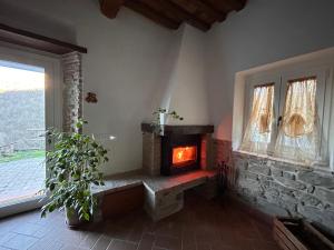 sala de estar con chimenea de piedra y ventana en La casa del Tiglio, en Borgo San Lorenzo