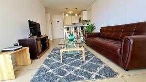 MC Suite Norte - Vista al mar في أنتوفاغاستا: غرفة معيشة مع أريكة جلدية وطاولة زجاجية