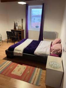 a bedroom with a bed and a window and a table at chambre violette coté aéroport calme charmante in Pusignan