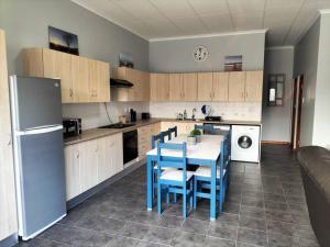 a kitchen with a table and blue chairs in it at Bydistrand Stillbay in Stilbaai