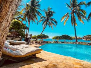 a resort swimming pool with palm trees and the ocean at VOVO TELO LODGE in Toliara