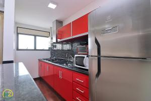 La cuisine est équipée de placards rouges et d'un réfrigérateur en acier inoxydable. dans l'établissement Linda Cobertura duplex com varanda e piscina, à Rio de Janeiro