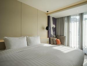 Stay Plus Hotel Bangkok في بانكوك: غرفة نوم بسرير ابيض كبير ونافذة