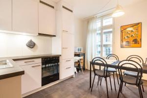 a kitchen with white cabinets and a table with chairs at Central City - inkl Parking and Bern Ticket in Bern