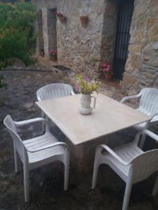 een tafel met vier stoelen en een vaas met bloemen erop bij Casa Rural en pleno paraje natural La Chirala in Enguera